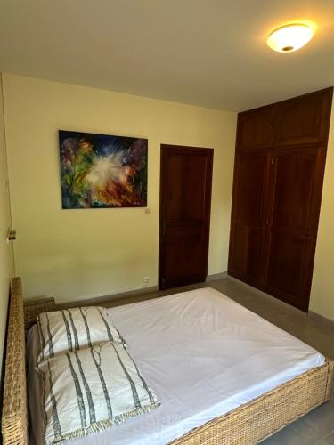 a bedroom with a bed and a painting on the wall at Between us : Chambres d’hôtes à Saint joseph in Saint-Joseph