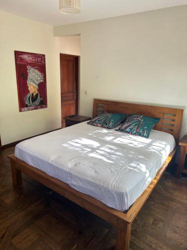 - une chambre avec un grand lit et un cadre en bois dans l'établissement Between us : Chambres d’hôtes à Saint joseph, à Saint-Joseph