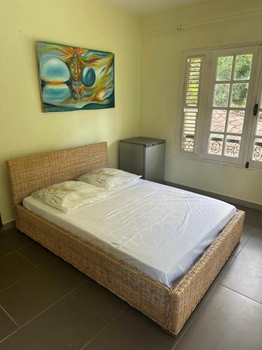 uma cama num quarto com um quadro na parede em Between us : Chambres d’hôtes à Saint joseph em Saint-Joseph