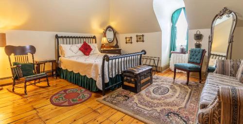 a bedroom with a bed and two chairs and a mirror at Fitzroy Hall in Charlottetown