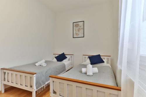 Studio Suite mit Service wie im Hotel في غوبينغِن: سريرين في غرفة بجدران بيضاء ووسائد زرقاء