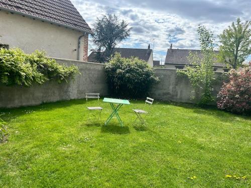 een tafel en twee stoelen in een tuin met een hek bij Maison proche commerces in Romorantin
