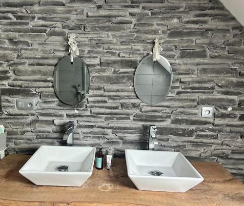 twee wastafels voor een stenen muur met spiegels bij Maison proche commerces in Romorantin