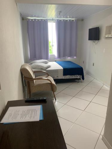 a bedroom with a bed and a desk with a keyboard at SUITES Recanto do DO Mar in Saquarema