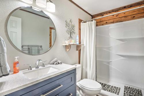 La salle de bains est pourvue d'un lavabo, de toilettes et d'un miroir. dans l'établissement Secluded Table Rock LakeandBranson Cabin with Hot Tub!, à Kimberling City
