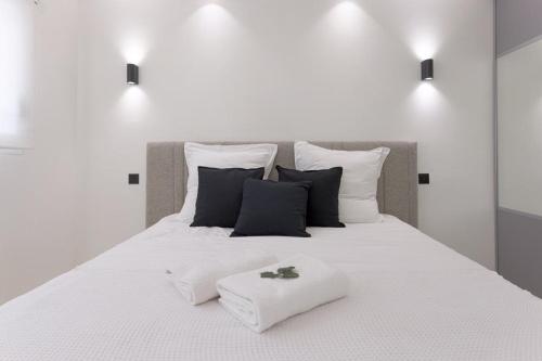 - un lit blanc avec des oreillers noirs et blancs dans l'établissement Lunique Maubourg - Next Hôtel Martinez - terrasse, à Cannes