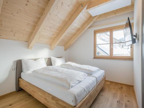 Schlafzimmer mit einem Bett mit weißer Bettwäsche und einem Fenster in der Unterkunft Bergzauber in Donnersbachwald