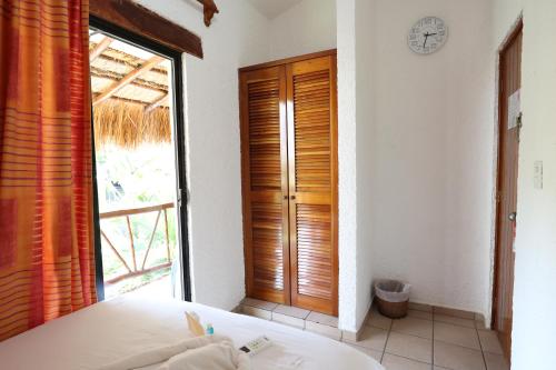 a bedroom with a bed and a window with a clock at Hotel Bosque Caribe, 5th Av. zone in Playa del Carmen