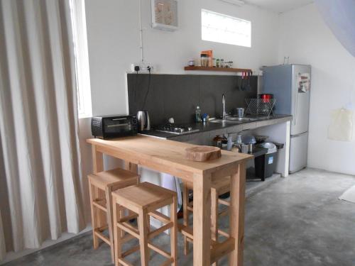 een keuken met een houten tafel en een koelkast bij Le Havre Gourmand in Rodrigues Island