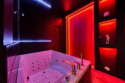La salle de bains est pourvue d'une baignoire blanche avec des lumières rouges. dans l'établissement Suite Deluxe - Jacuzzi, à Melun