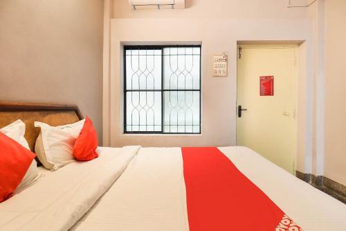 a bed with red and white pillows and a window at OYO Flagship Hotel Achi in Tiruppūr