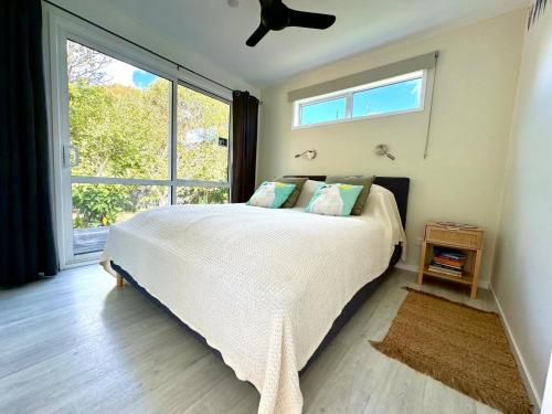 a bedroom with a bed and a large window at Four Huia in Oneroa
