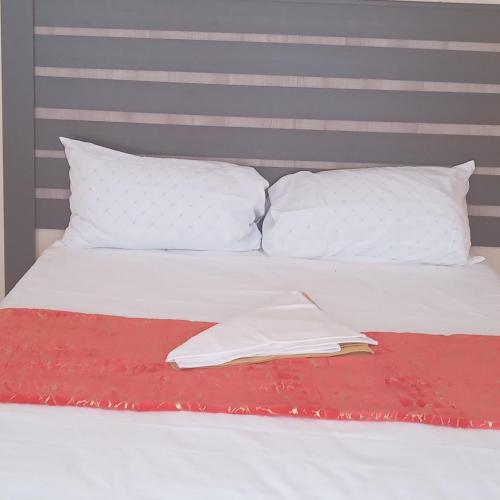 uma cama branca com almofadas brancas e um livro sobre ela em Sandton guesthouse em Ga-Manapane