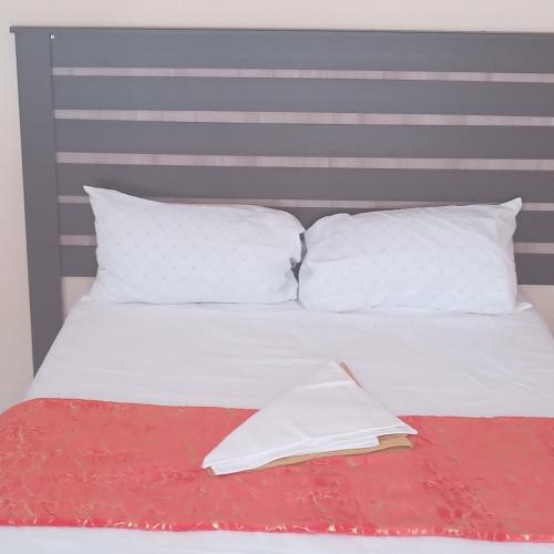uma cama com almofadas brancas e um livro sobre ela em Sandton guesthouse em Ga-Manapane