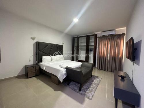 a bedroom with a bed and a chair and a television at AJAH LAGOS in Lekki