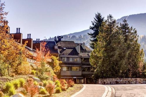 a building in the mountains with trees and a road at 1Bd Unit In the heart of Whistler Village in Whistler