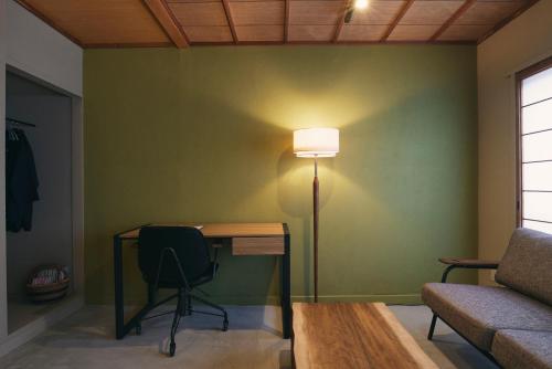 a room with a desk with a lamp and a couch at Hanaguri-しまなみ海道スマート旅館 in Ikata