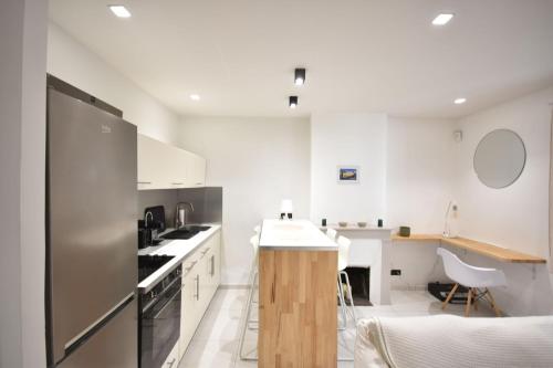 - une cuisine avec des murs blancs et un réfrigérateur en acier inoxydable dans l'établissement Nice 37 m with garden in Marseille, à Marseille