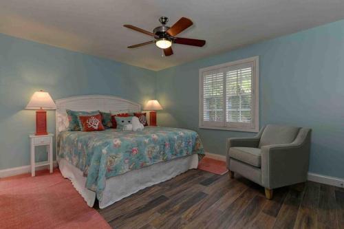 a bedroom with a bed and a ceiling fan and a chair at Surrounded By Sea Breezes - Anna Maria, FL in Anna Maria