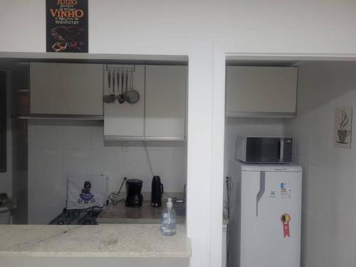 a kitchen with a microwave and a refrigerator at Apartamento com varanda Reserva do Sahy in Mangaratiba