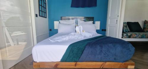 a bedroom with a white bed with blue walls at La villa Tina in Ducos