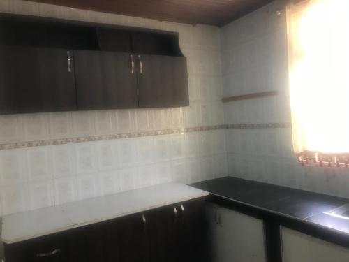 une cuisine vide avec des armoires noires et une fenêtre dans l'établissement King Makeri Guest House, à Ogbojo