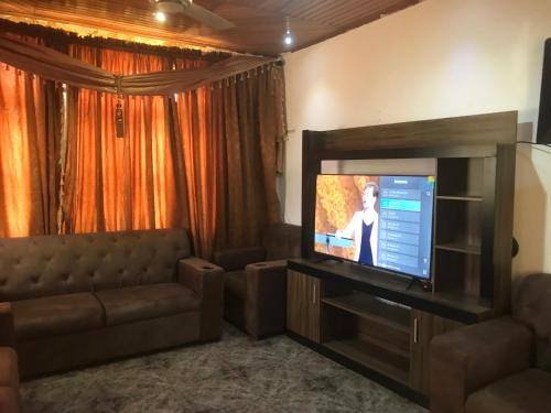 Il comprend un salon doté d'un canapé et d'une télévision à écran plat. dans l'établissement King Makeri Guest House, à Ogbojo