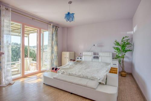 ein weißes Schlafzimmer mit einem Bett und einem großen Fenster in der Unterkunft Casa Lola in Tiana