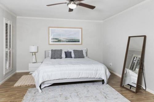 a white bedroom with a bed and a mirror at Houston Luxury 4br/3ba and Pool in Sugar Land