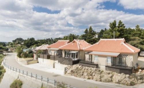 a row of houses with red roofs on a road at Starsビーチまで徒歩2分 古宇利島の自然に囲まれた非日常体験 in Nakijin