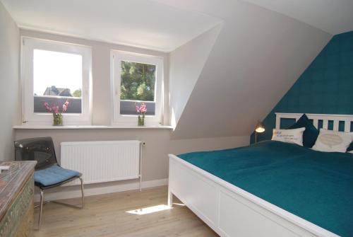 ein Schlafzimmer mit einem Bett und zwei Fenstern in der Unterkunft Ferienhaus Westhüs in Tinnum