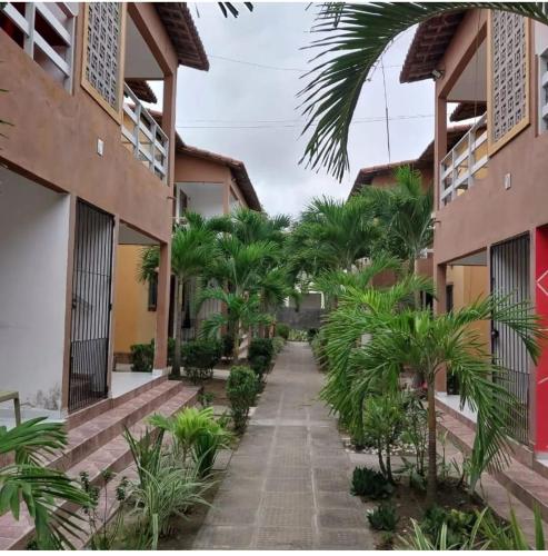 a walkway between two buildings with palm trees at Residencial Jardins Ilha de Itamaracá in Vila Velha
