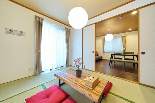 a living room with a wooden table and pink chairs at The Prime TOKYO HANEDA in Tokyo