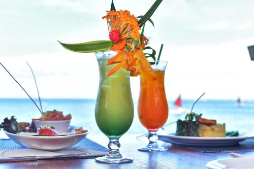 a table with two cocktails and plates of food at Royal Tahitien in Papeete
