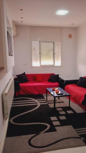 sala de estar con sofá rojo y mesa en Kalthoum en Chott Meriem