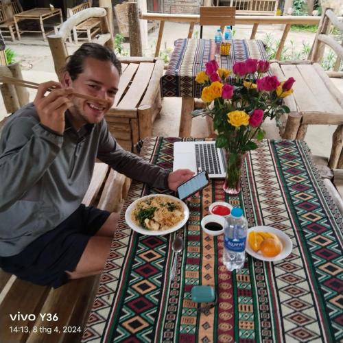 a man sitting at a table with a plate of food at MAI HICH FARMSTAY 2 in Mai Hạ