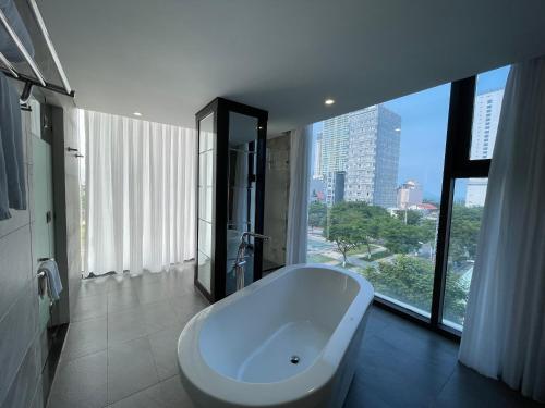 a white bath tub in a bathroom with a large window at Danaciti Hotel in Danang