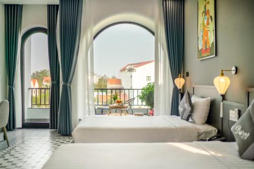 ホイアンにあるVilla Dương Hội Anの大きな窓付きの客室で、ベッド2台が備わります。