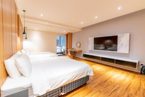 a bedroom with two beds and a flat screen tv at Sunshine Palm B&B in Magong