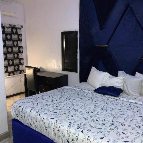 a bedroom with a bed with a blue headboard and a desk at BLUE MOON HOTELS VICTORIA ISLAND in Lagos