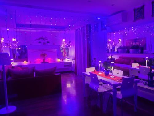 ein Wohnzimmer mit violetter Beleuchtung sowie Tischen und Stühlen in der Unterkunft Charme e Benessere in home suite in Portici