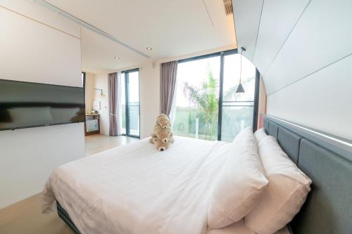 a teddy bear sitting on a bed in a bedroom at Sunshine Palm B&B in Magong