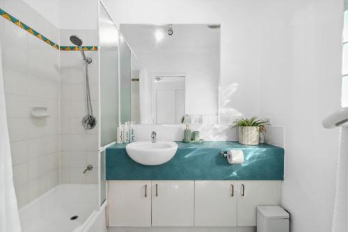 a bathroom with a white sink and a tub and a sink at Oasis - Pool, Wifi & Free Parking in Cairns