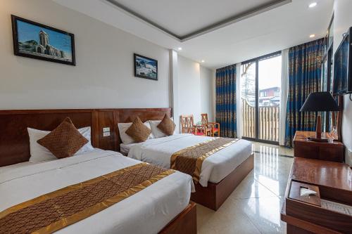 a hotel room with two beds and a balcony at Sapa Hai Yen Hotel and Apartment in Sa Pả