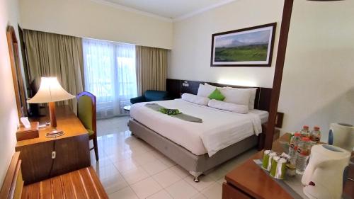 Habitación de hotel con cama y escritorio en Grand Whiz Hotel Trawas Mojokerto, en Trawas