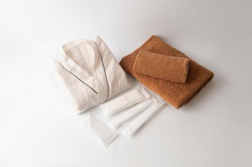un par de servilletas de tela y toallas de fondo blanco en HOTEL R9 The Yard 小美玉, en Omitama