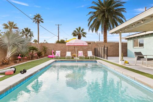 a swimming pool with chairs and an umbrella next to a house at Desert Dream - Old Town Mid-Century Modern - Heated Pool in Scottsdale