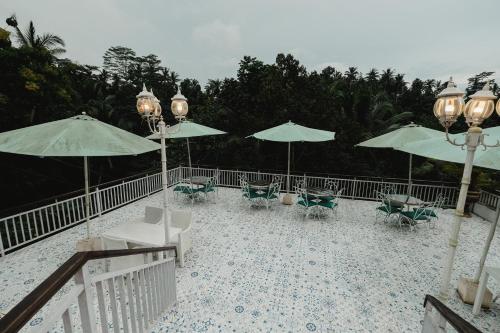 a patio with tables and chairs and umbrellas at Royal Maharani Payogan in Ubud