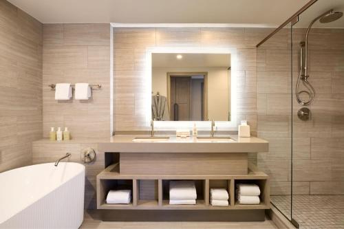 ein Badezimmer mit einem Waschbecken, einer Badewanne und einem Spiegel in der Unterkunft JW Marriott St Maarten Beach Resort & Spa in Dawn Beach