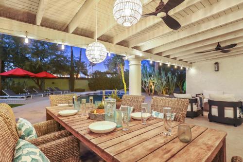 a wooden table in a patio with chairs and lights at Olive Tree Retreat - Heated Pool, Patio & Privacy in Scottsdale